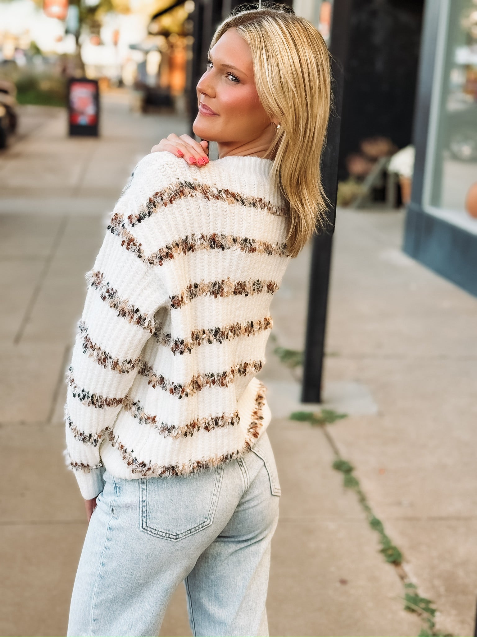 White v neck button down cardigan with multi color stripes.