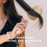 Person using a gold hairbrush on their hair with text about its use for everyday drying and blowouts.