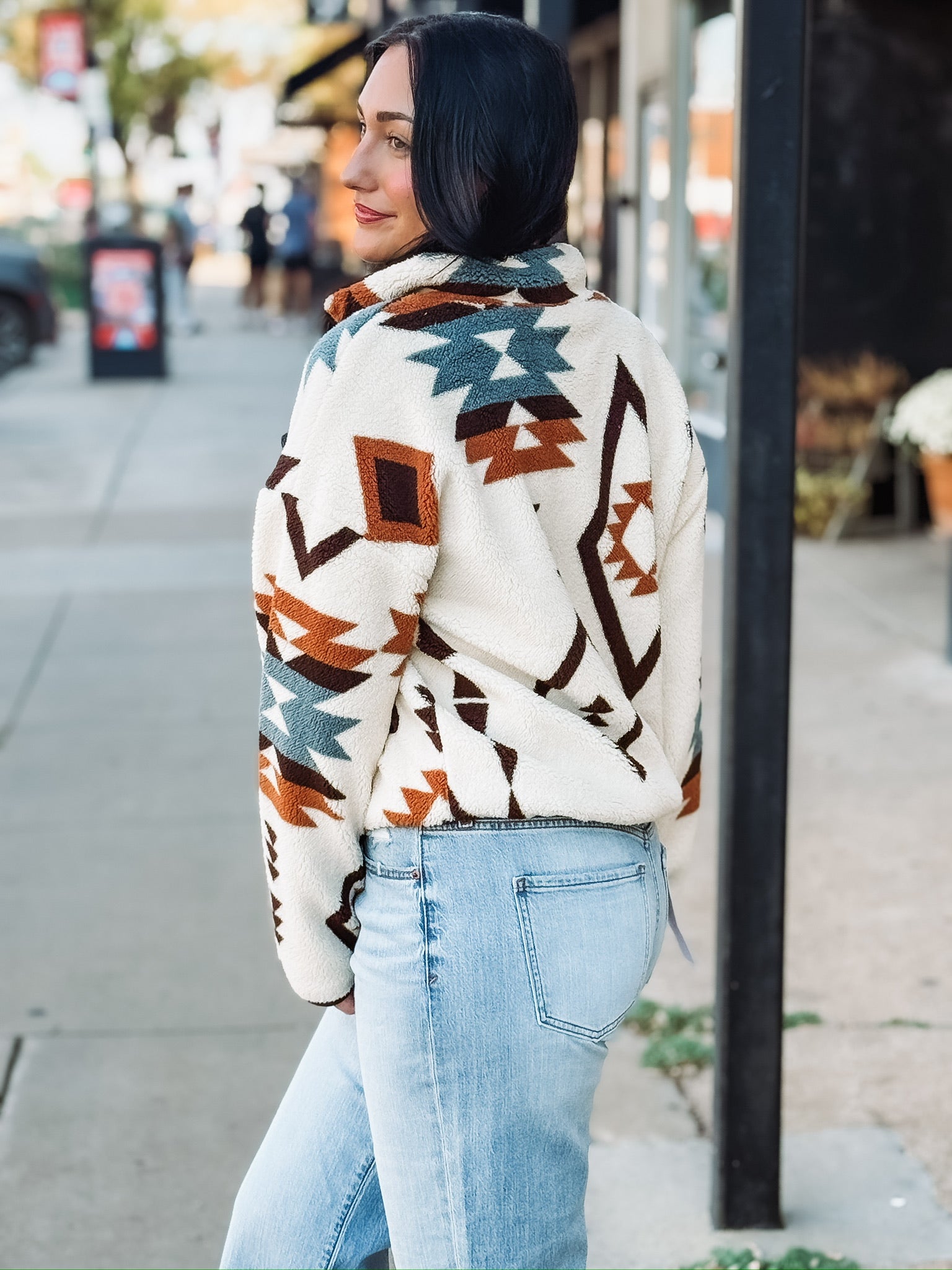 Aztec brown, rust, and turquoise print on a cream sherpa zip up jacket.