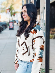 Aztec brown, rust, and turquoise print on a cream sherpa zip up jacket.