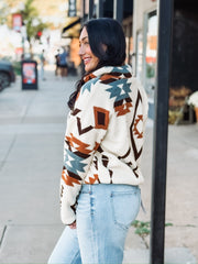 Aztec brown, rust, and turquoise print on a cream sherpa zip up jacket.
