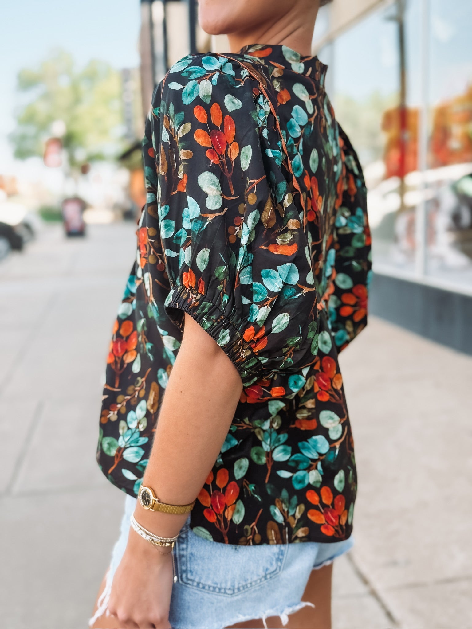 Black short sleeve floral v neck with elastic sleeves and orange and green detailing.
