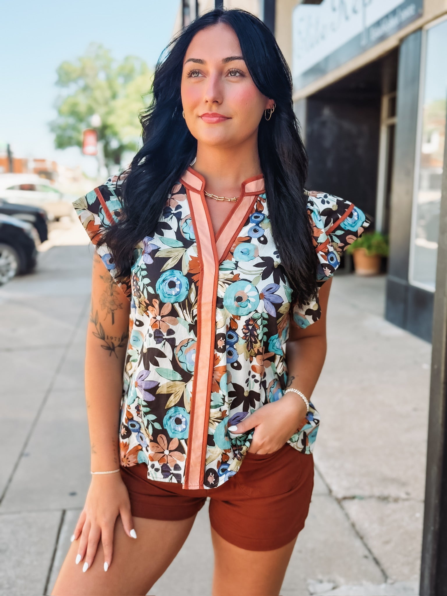 Flutter cap sleeve floral top with orange contrast seaming.