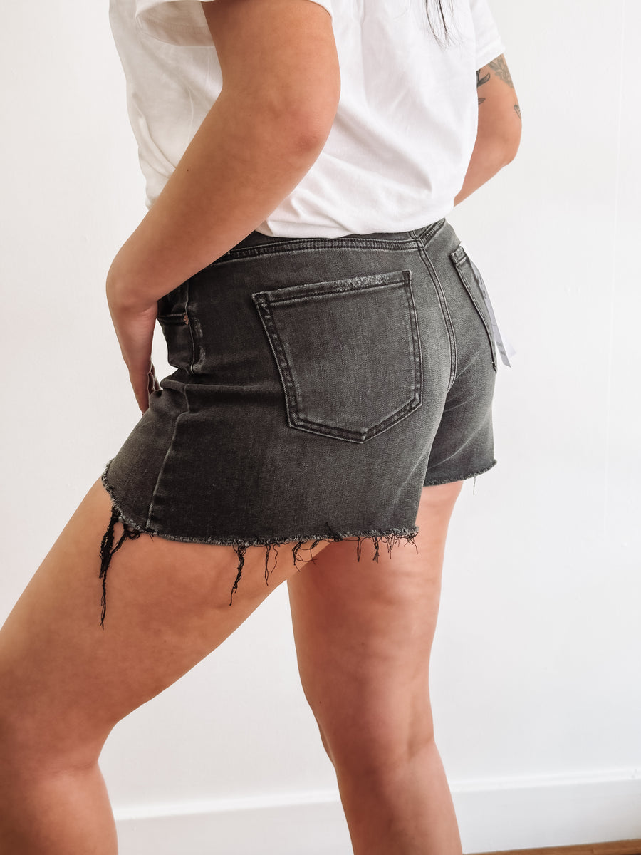 Black distressed denim shorts by Daze.