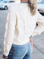 Person wearing a cream sweater with a blurred background