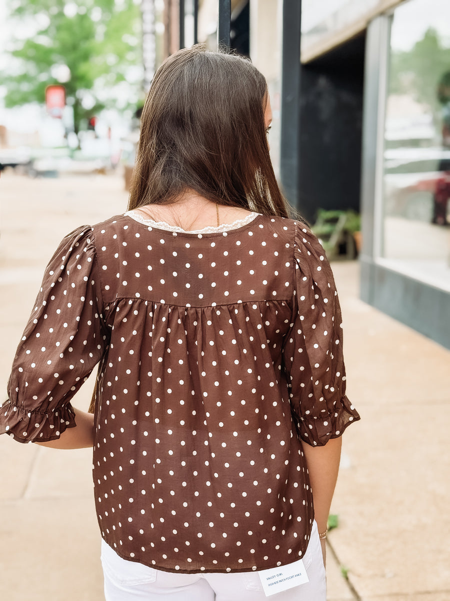 Woman wearing a brown polka dot blouse outdoors