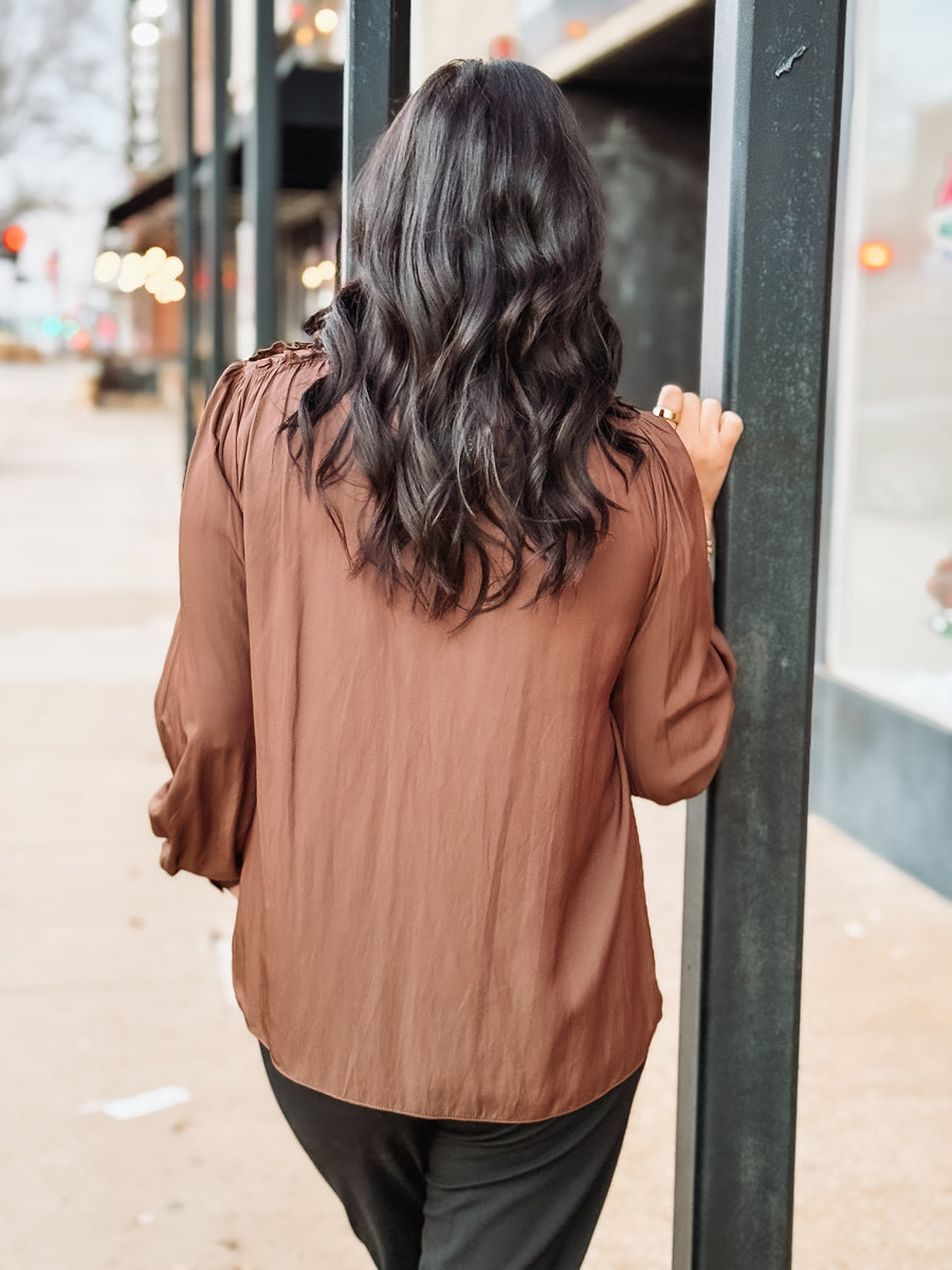 Brown long sleeve satin blouse with ruffle shoulders.