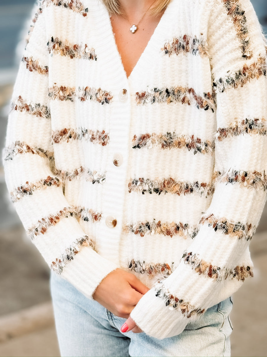 White v neck button down cardigan with multi color stripes.