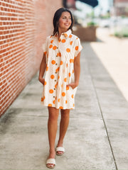 Cream mini dress with an orange polka dot print, button front closure, short sleeves, side pockets, and a relaxed fit.