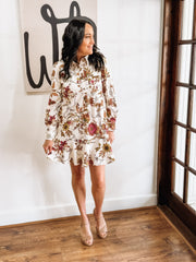 Cream long-sleeve floral dress with a flowy hem. and button details.