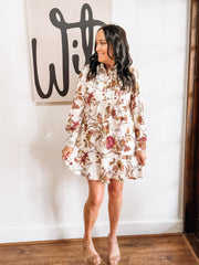 Cream long-sleeve floral dress with a flowy hem. and button details.