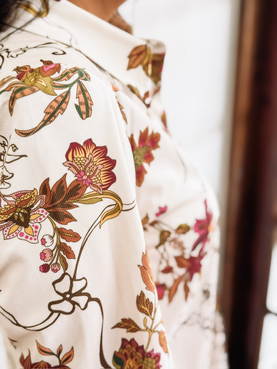 Cream long-sleeve floral dress with a flowy hem. and button details.