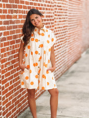 Cream mini dress with an orange polka dot print, button front closure, short sleeves, side pockets, and a relaxed fit.