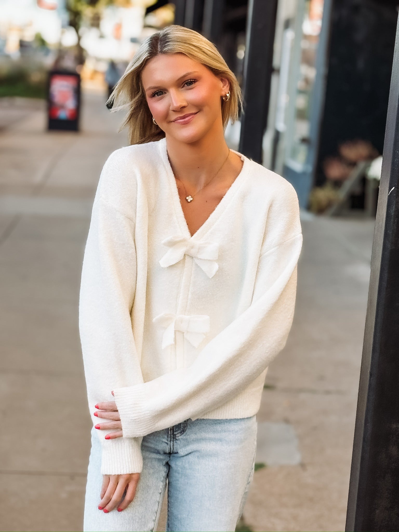 Cream v neck long sleeve sweater with snap button bow ties.
