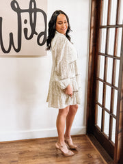 Dainty olive floral print on a cream long sleeve mini dress that features tiers and a slight v neck.