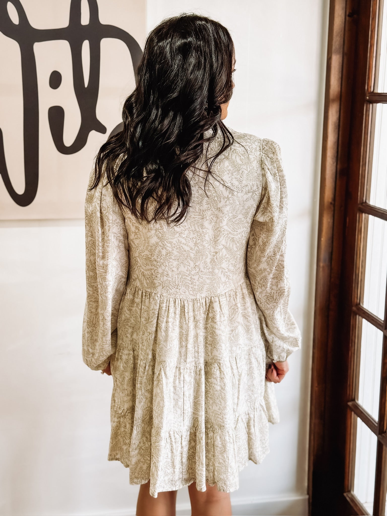 Dainty olive floral print on a cream long sleeve mini dress that features tiers and a slight v neck.