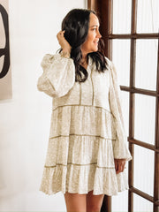Dainty olive floral print on a cream long sleeve mini dress that features tiers and a slight v neck.