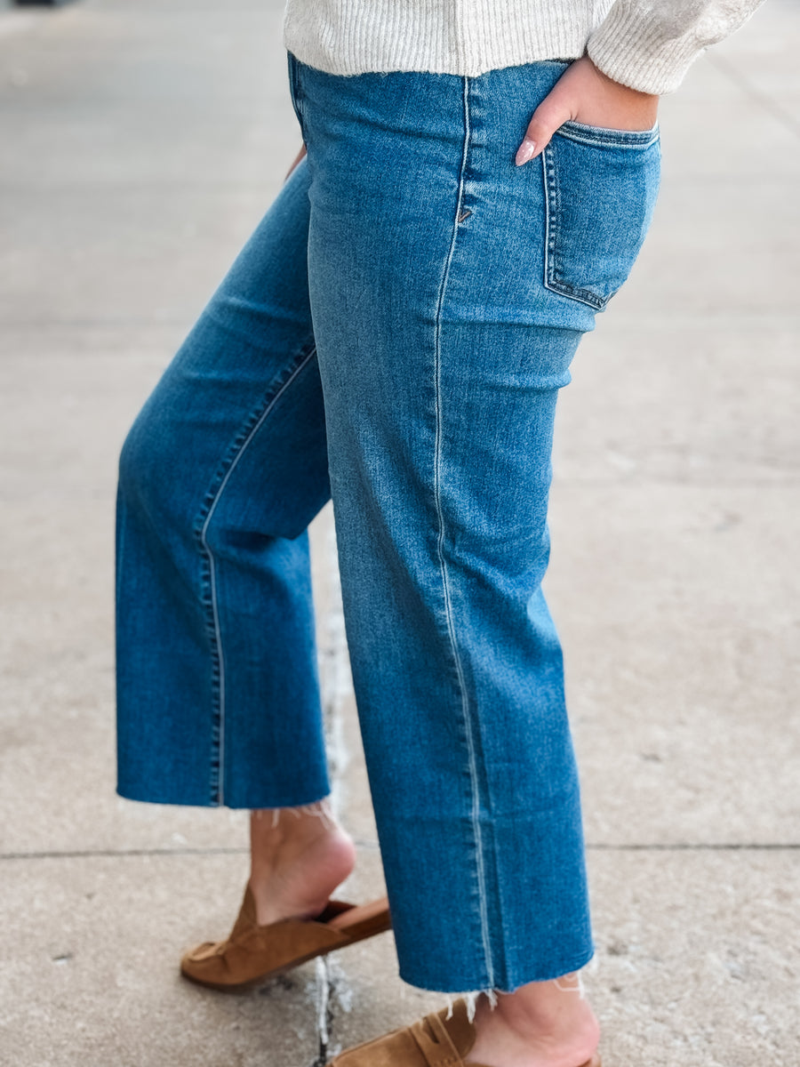 Person wearing blue jeans and a white sweater on a neutral background