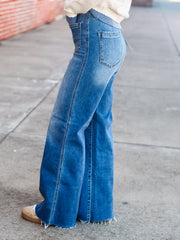 Blue flared jeans worn by a person on a concrete surface