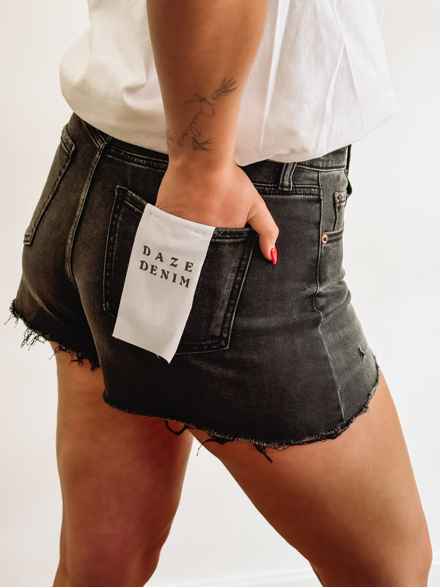Black distressed denim shorts by Daze.