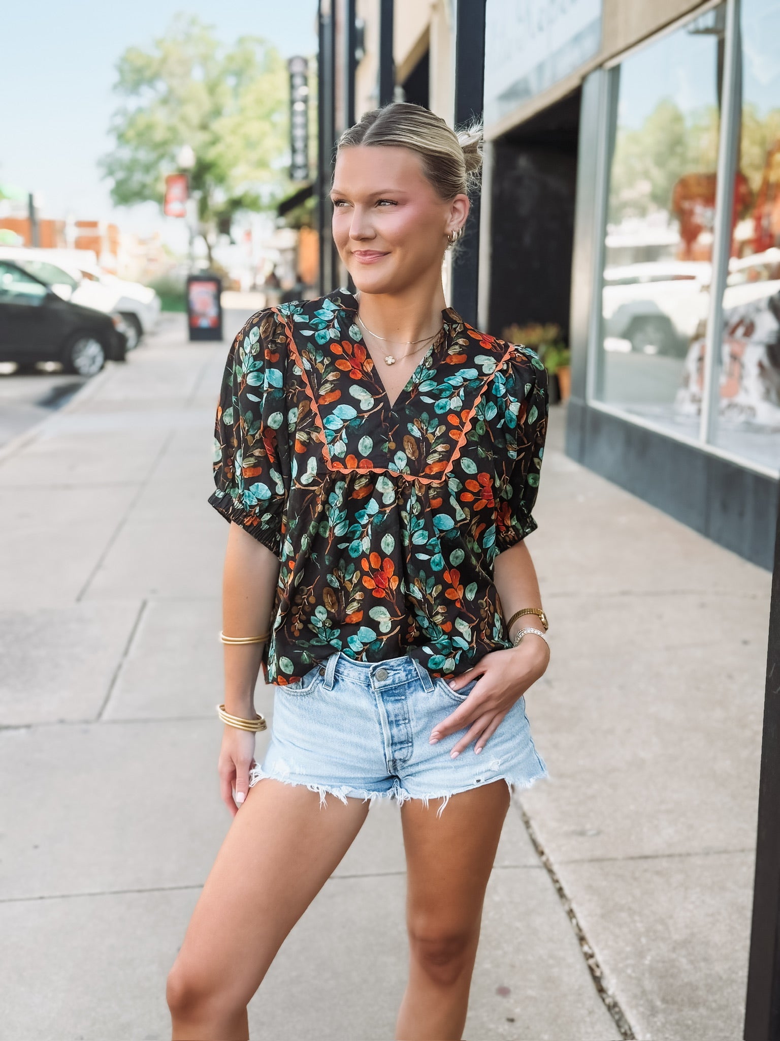 Black short sleeve floral v neck with elastic sleeves and orange and green detailing.