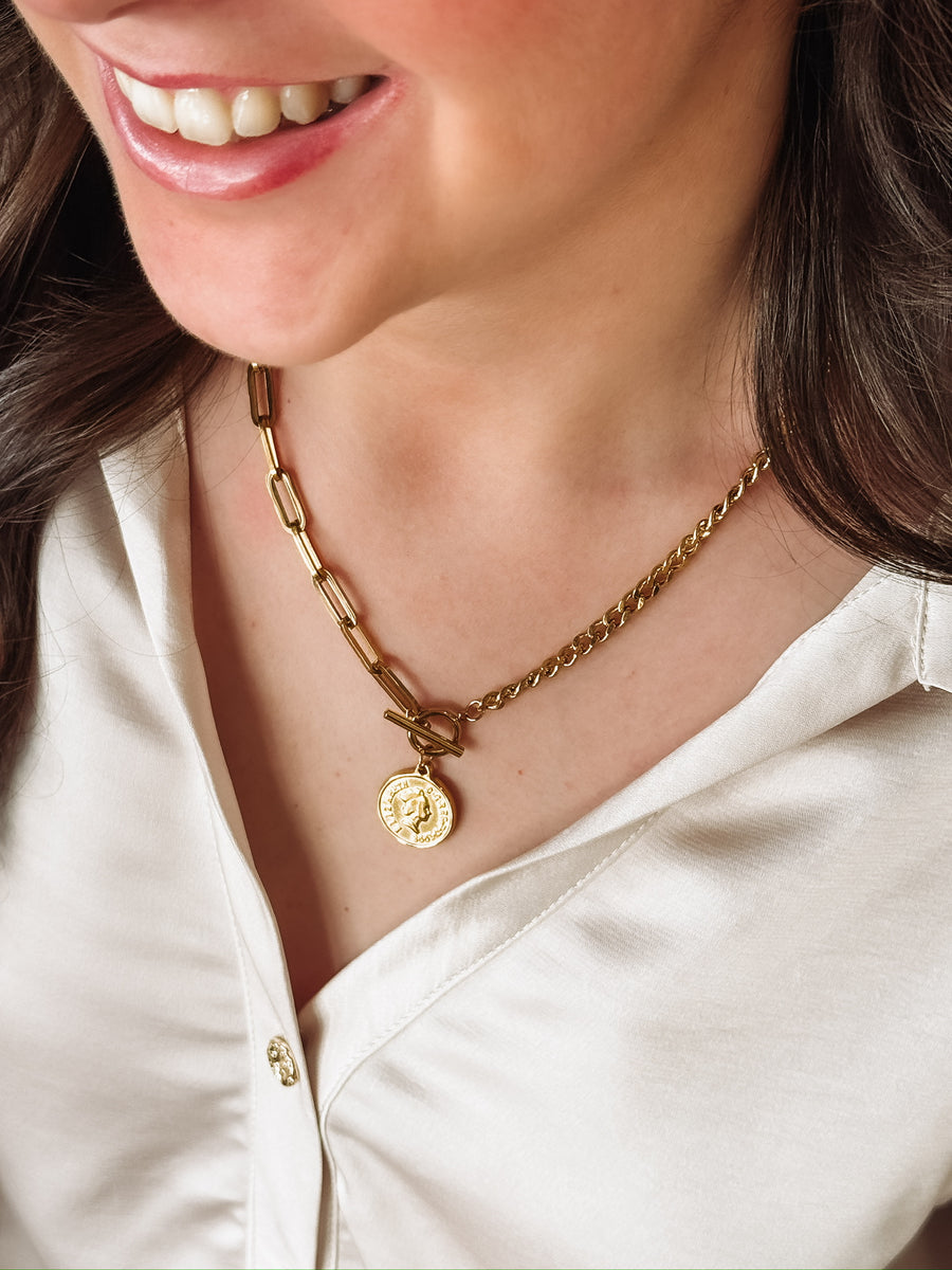 Gold mixed chain necklace with a toggle closure and a small coin pendant.