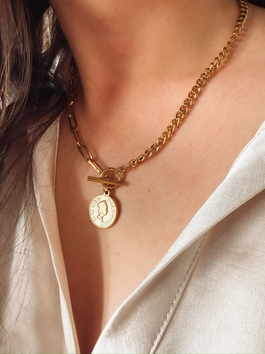 Gold mixed chain necklace with a toggle closure and a small coin pendant.