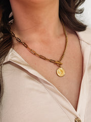 Gold mixed chain necklace with a toggle closure and a small coin pendant.