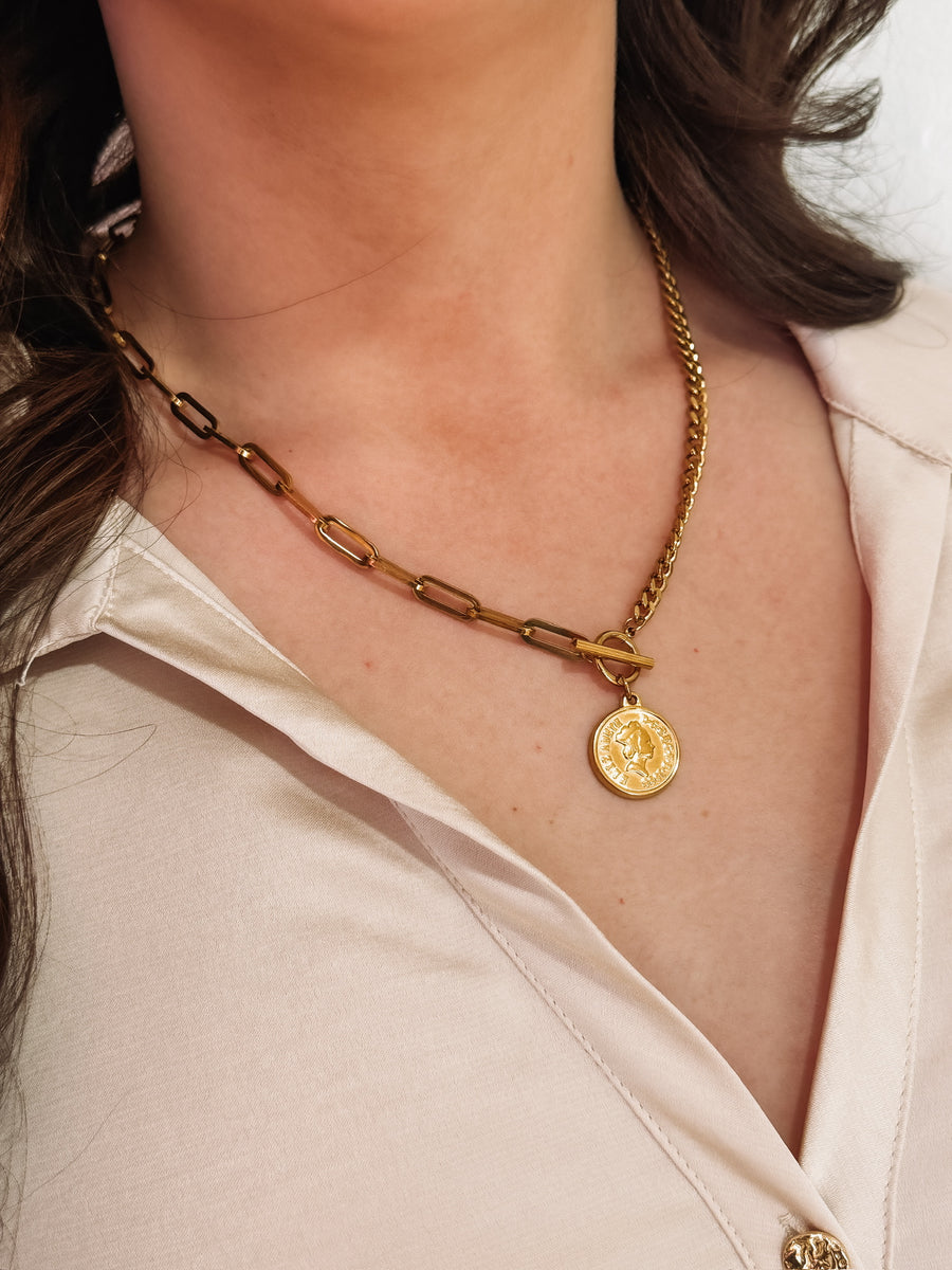 Gold mixed chain necklace with a toggle closure and a small coin pendant.