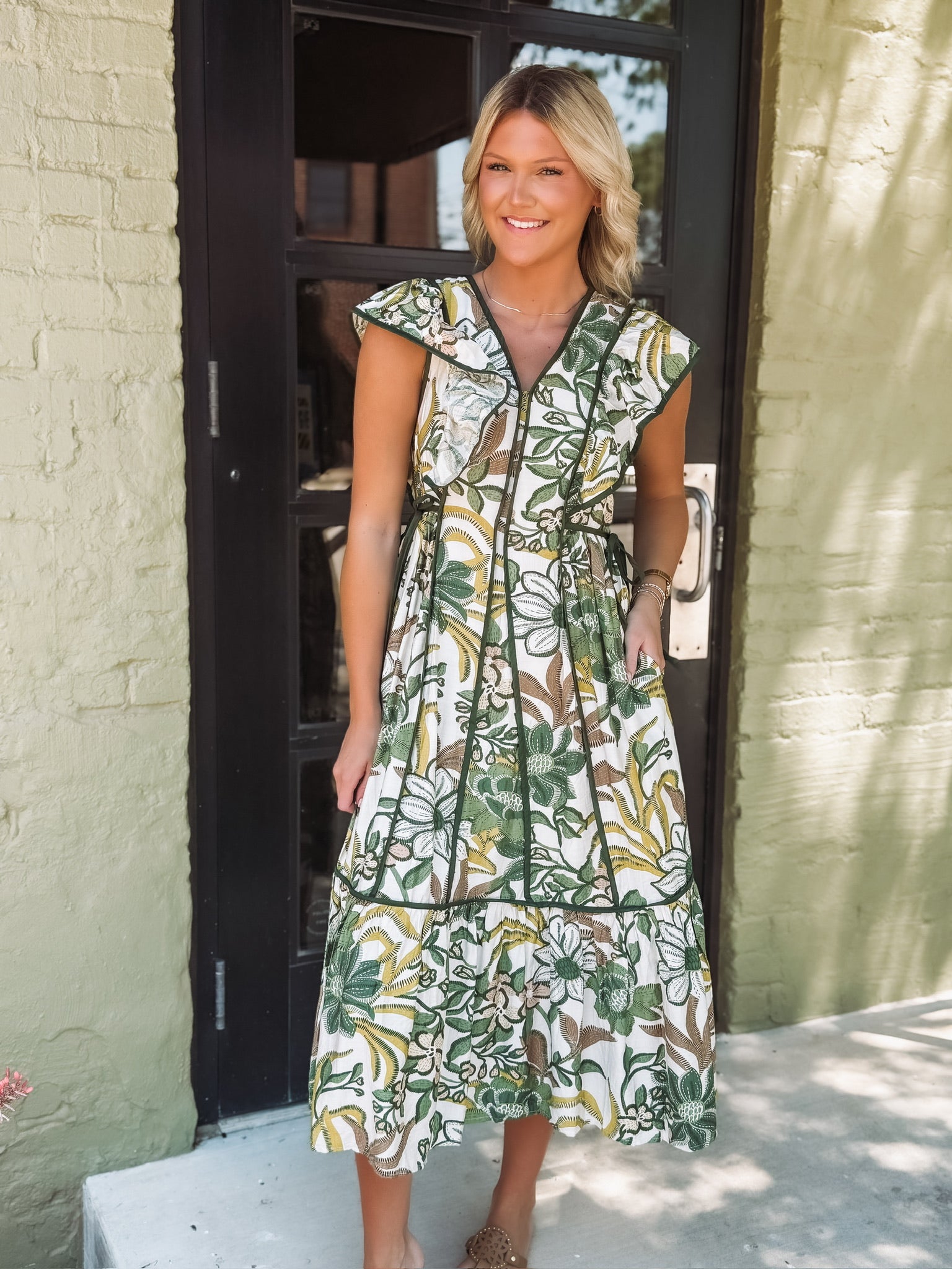 Woman wearing a floral dress standing outside a building.