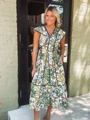 Woman wearing a floral dress standing outside a building.