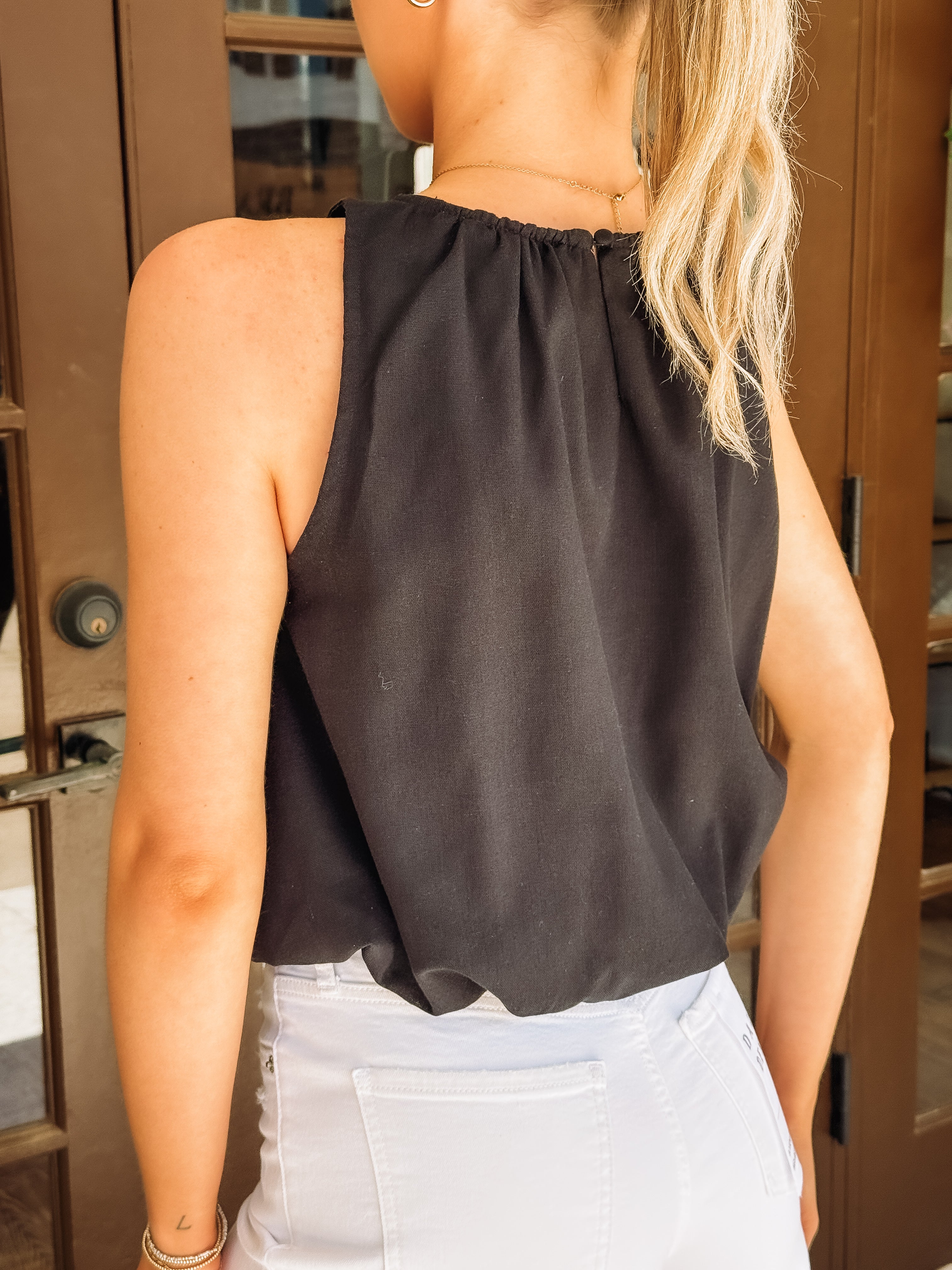 Black sleeveless bubble hemmed cropped tank.