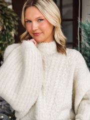 Large oversized mock neck sweater in cream with balloon sleeve and cable knit detailing.