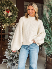 Large oversized mock neck sweater in cream with balloon sleeve and cable knit detailing.