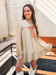 Long cream bubble sleeve mini dress with dainty floral detail and a laced bow detail.