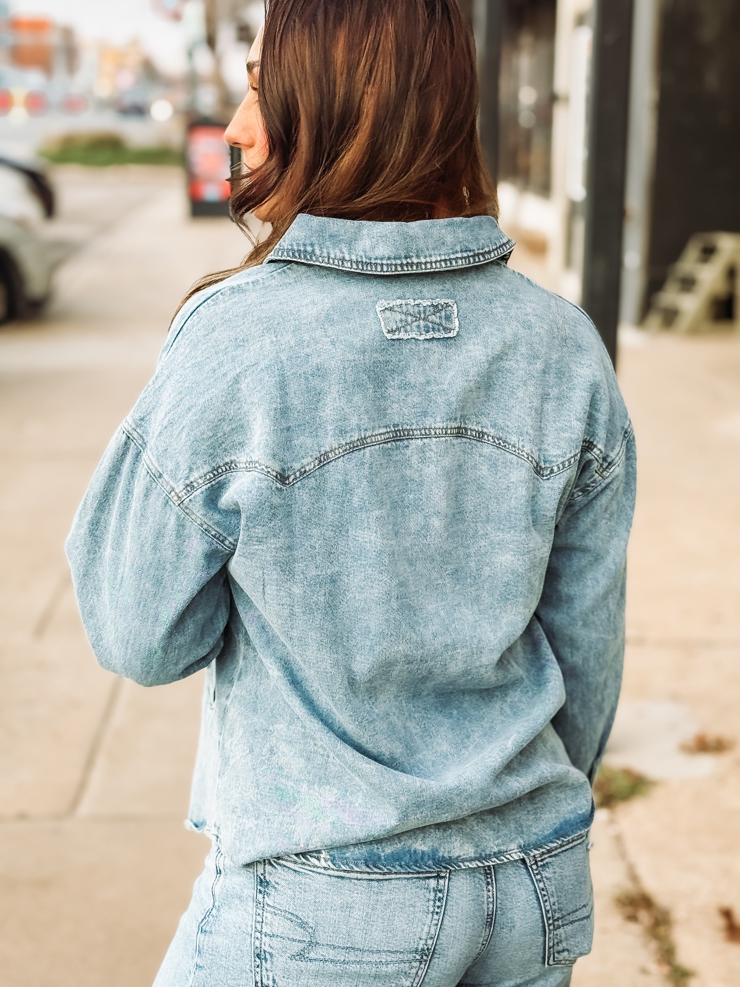 Pearl snap long sleeve denim top in a light wash with pockets.