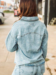 Pearl snap long sleeve denim top in a light wash with pockets.