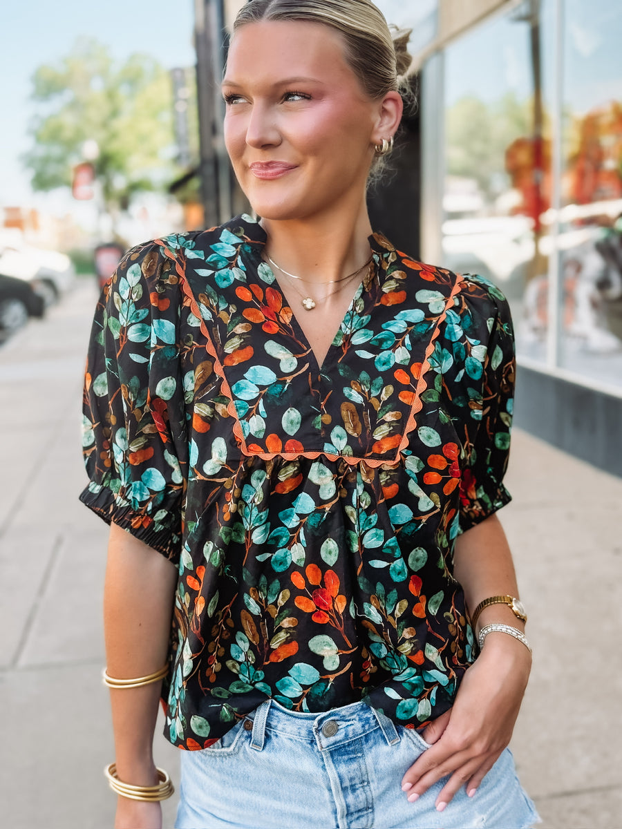 Black short sleeve floral v neck with elastic sleeves and orange and green detailing.
