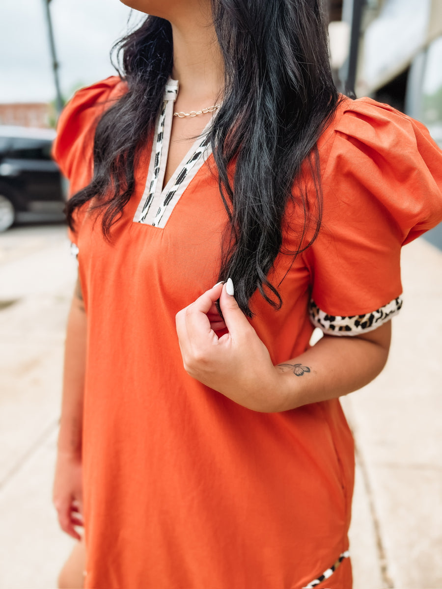 Orange above the knee length dress wit cheetah print trim.