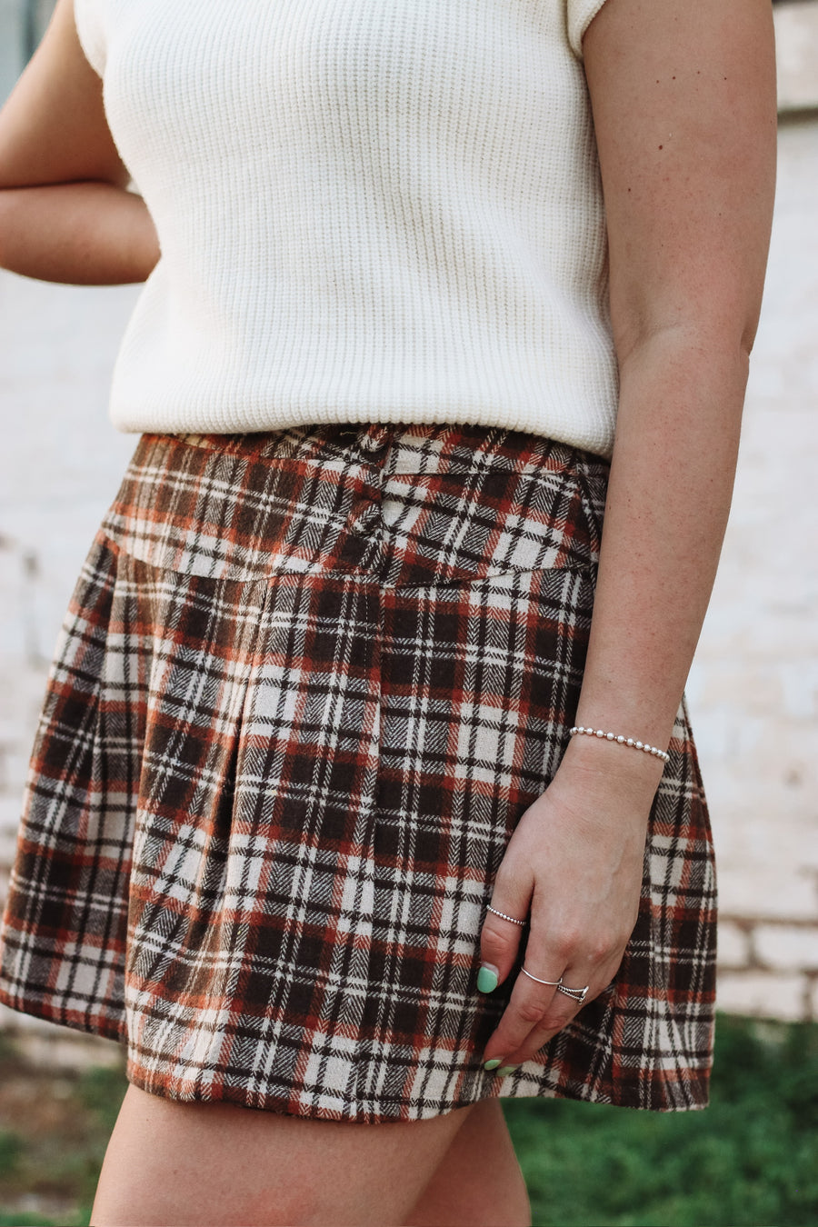 Brown, cream and rust plaid mini skort with side button detailing and loose pleats.