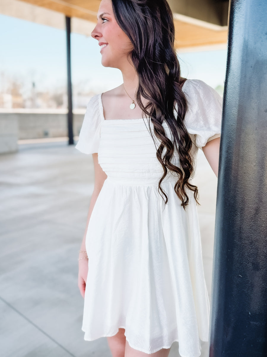 Ivory short sleeve pleated bodice mini dress.
