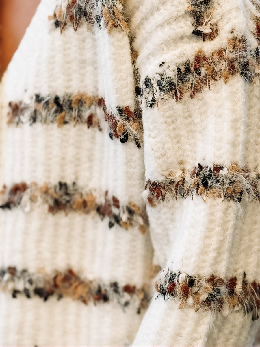 White v neck button down cardigan with multi color stripes.
