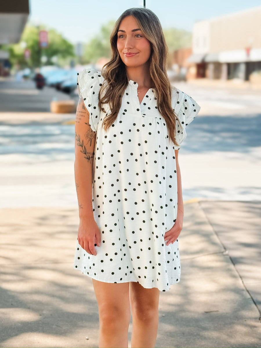 Off white flutter sleeve mini shift dress with black polka dots and a small v neckline.