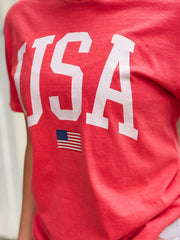 Red t-shirt with 'USA' and an American flag on a plain background