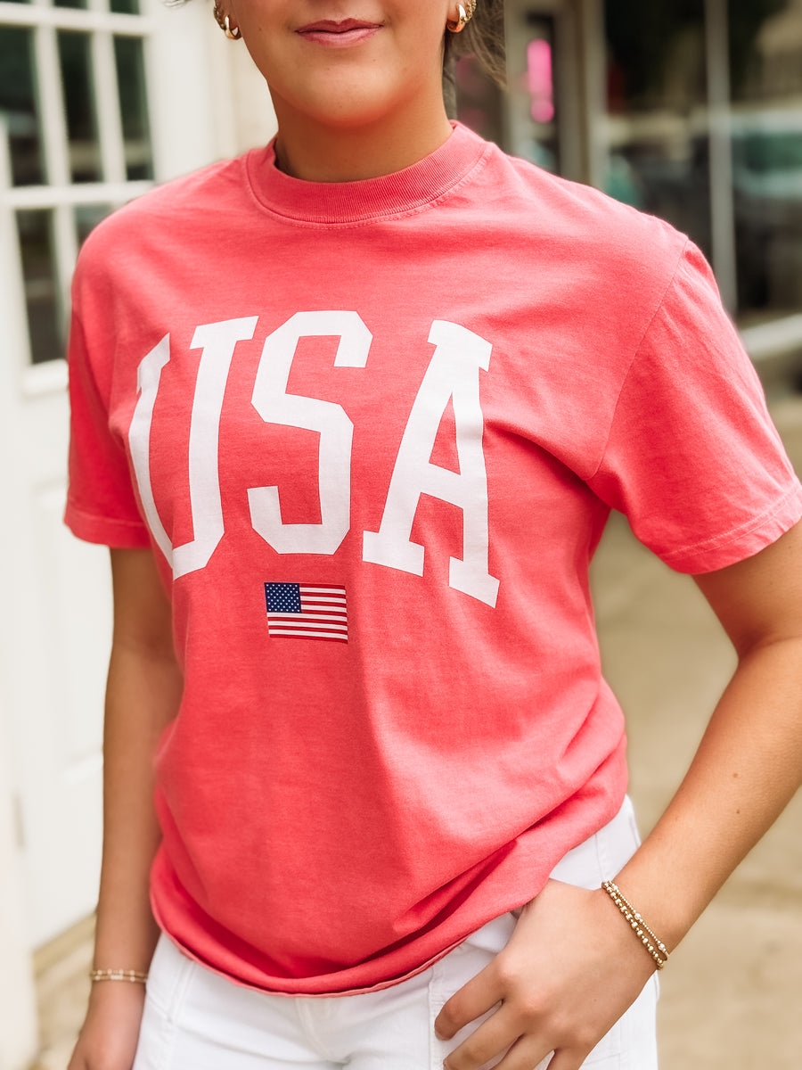 Person wearing a red 'USA' t-shirt with an American flag graphic.