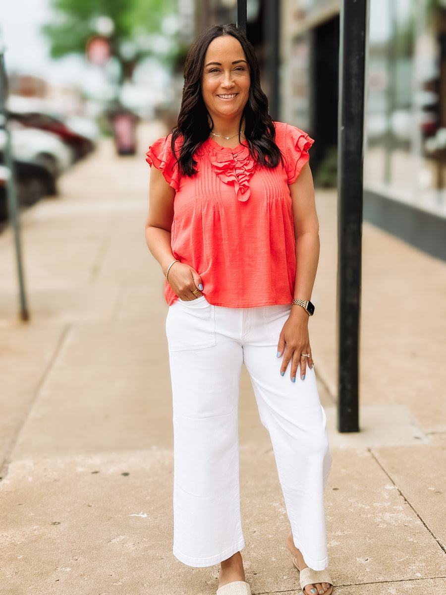woman on sidewalk wearing red blouse and white pants