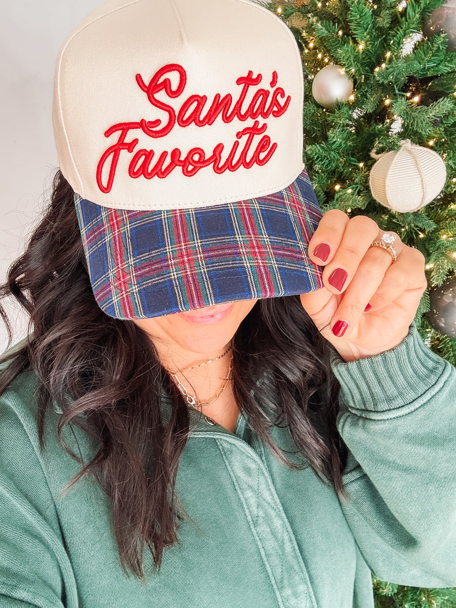 'Santa's Favorite' typography in red puff embroidery on a blue plaid and natural colored canvas hat.