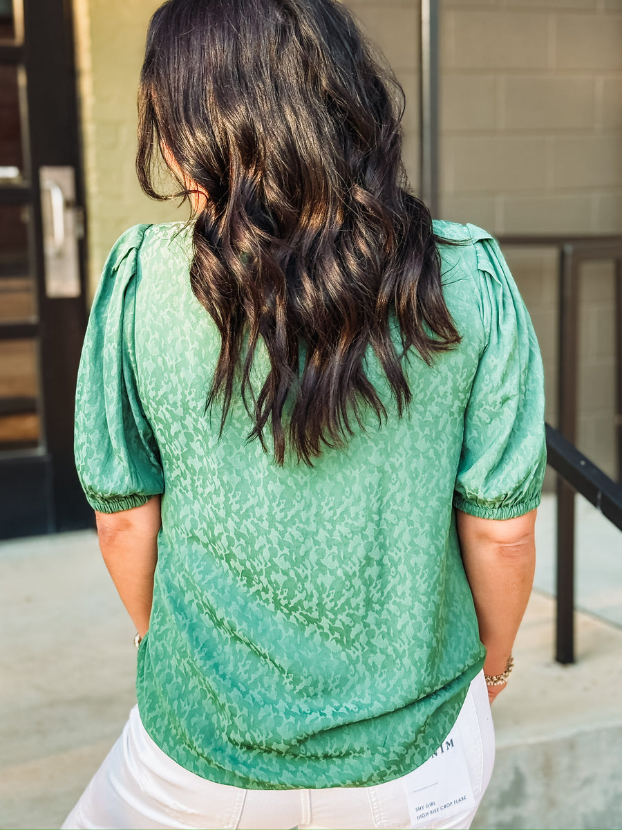 Green on green printed blouse with elastic short sleeves and a quarter button up crew neckline.