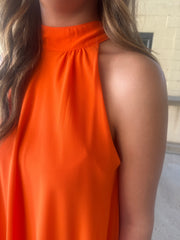 Bright orange mini dress with a mock neck, self-tie neckline, flowy silhouette, and tiered skirt.