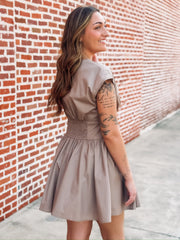 Taupe brown colored short sleeve mini dress. Features a full button front, a cinched waist and a V neckline. 
